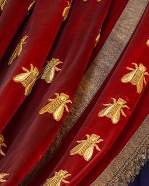 Kaiserliche Bienen in Gold auf rotem Samt gestickt — Detail vom Krönungsmantel Napoléons I., Sinnbild des Ersten Französischen Kaiserreichs