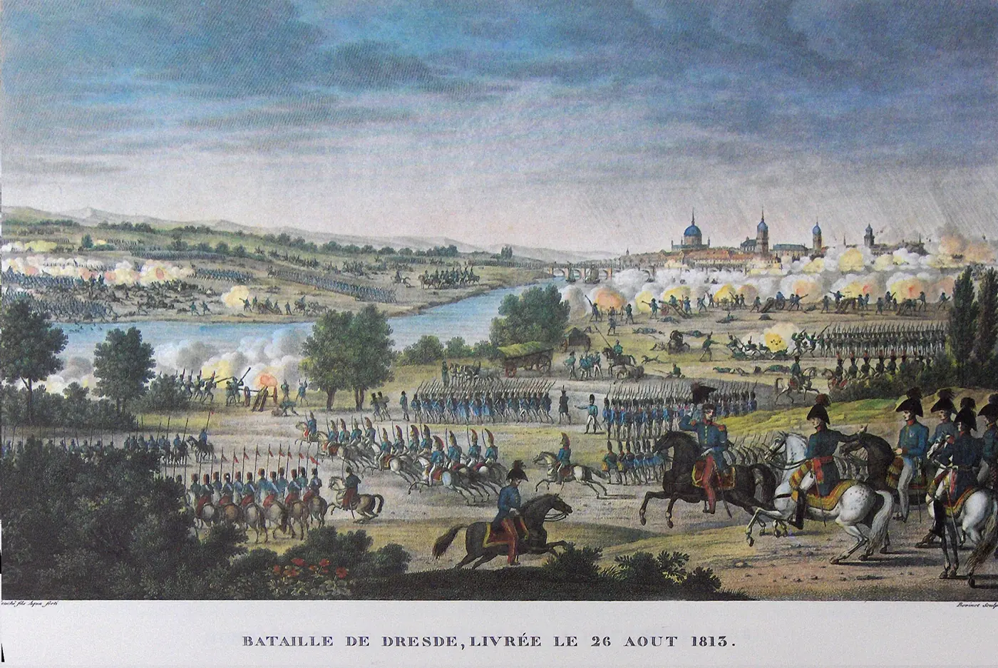 Kolorierter Stich: Im Vordergrund beobachtet eine Gruppe berittener Offiziere das Gefecht; in der Mitte rücken Infanterie- und Kavalleriekolonnen durch eine Ebene an der Elbe vor; in der Ferne die Kuppeln Dresdens und zahlreiche Rauchwolken