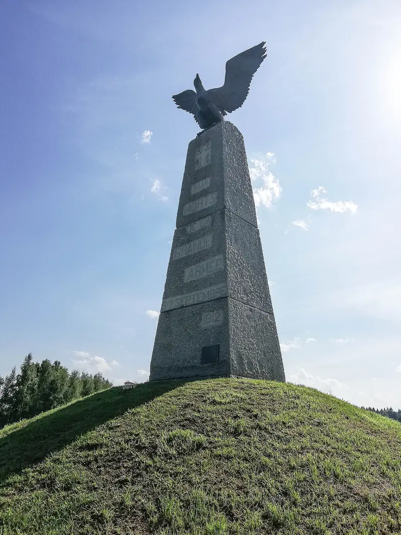 Obélisque de granit gris surmonté d'un aigle aux ailes déployées, au sommet d'une butte herbeuse