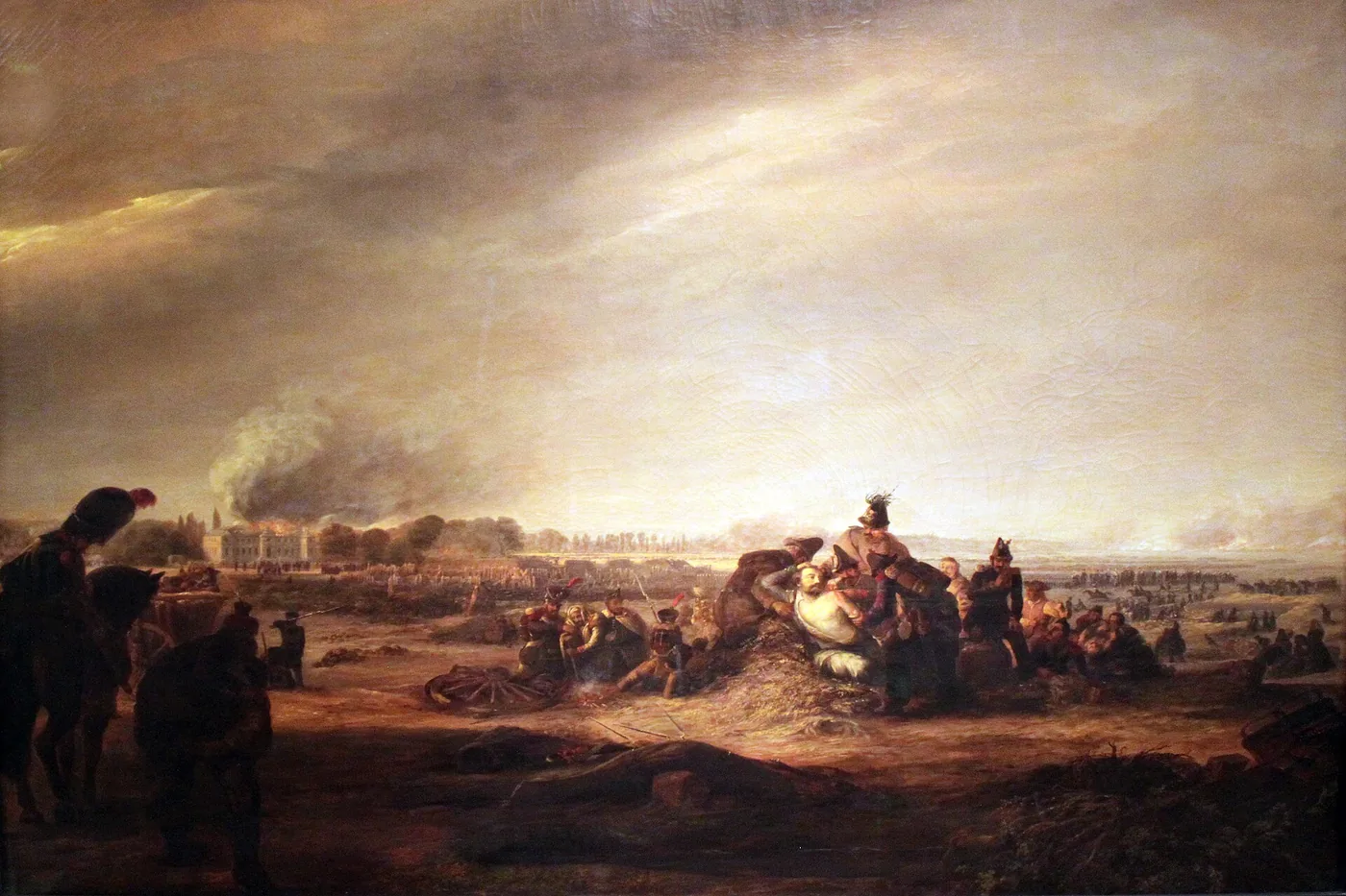 Sous un ciel d'orage, des soldats entourent un blessé à demi dévêtu étendu sur de la paille, près d'une roue brisée ; à l'arrière-plan, un palais en flammes et des troupes qui se déploient dans la plaine