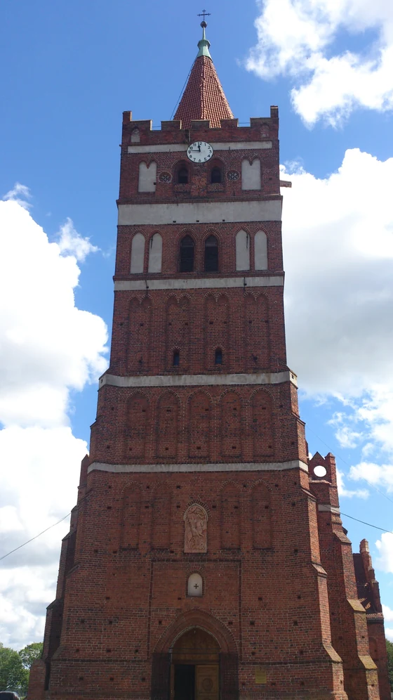 Tall red-brick Gothic bell tower with stepped gables under a blue sky