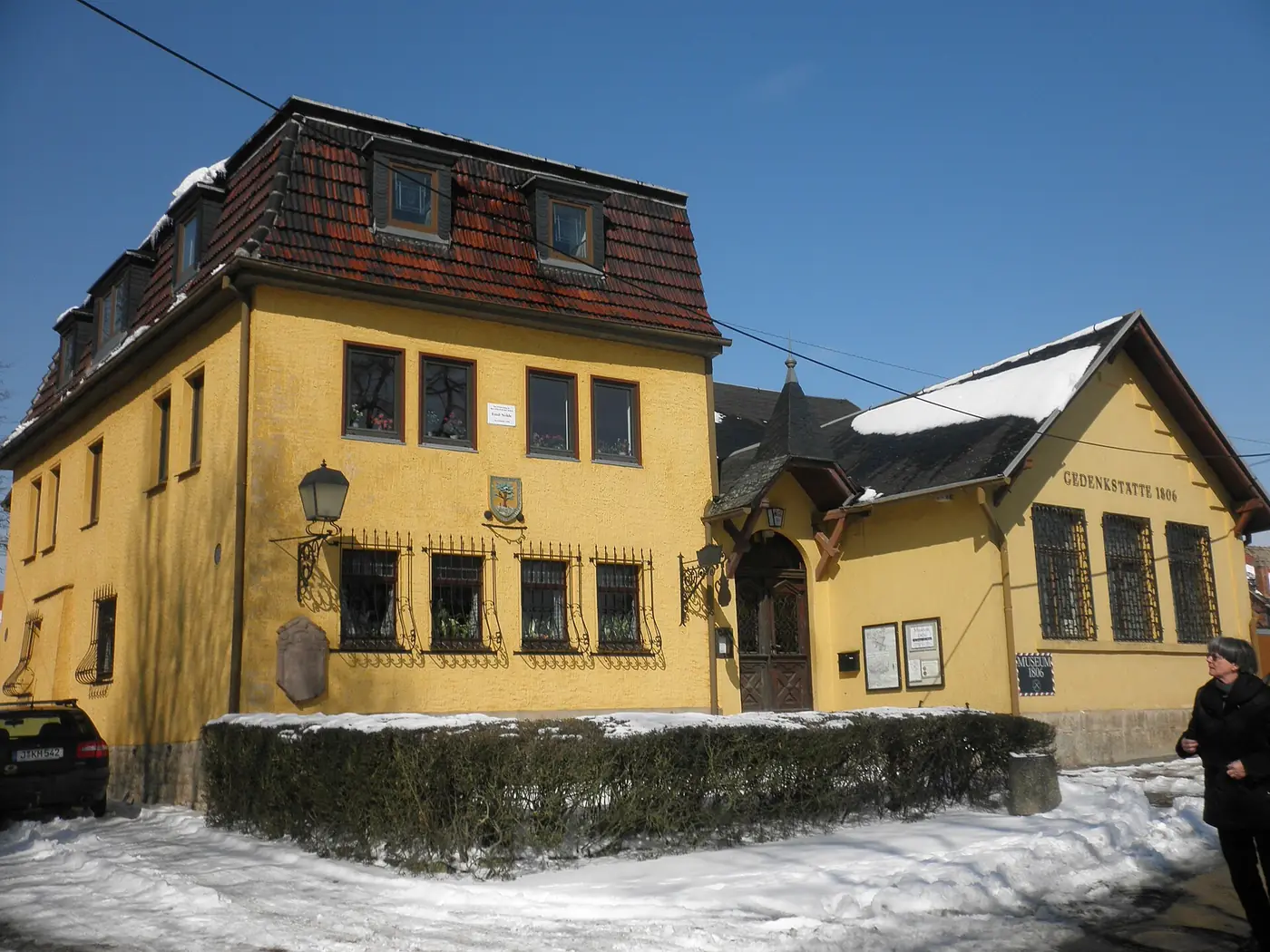 Edificio amarillo de tejado marrón de un museo de aldea, bajo la nieve