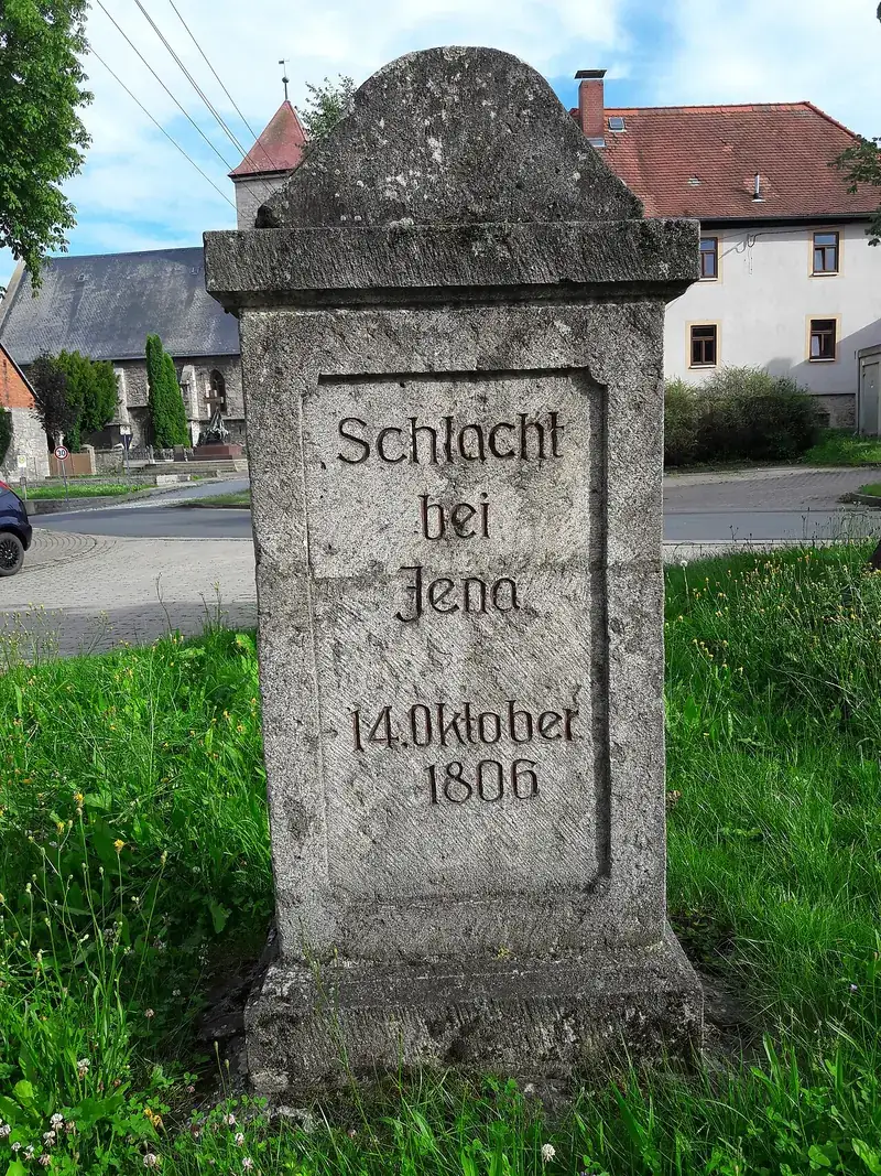Mojón de piedra grabado «Schlacht bei Jena, 14. Oktober 1806» junto a una calle de aldea