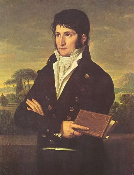 Portrait de Lucien Bonaparte, prince de Canino et frère de Napoléon Ier — huile néoclassique : jeune homme en redingote bleu marine à boutons métalliques, cravate blanche, bras croisés tenant un livre relié cuir ; terrasse, pins parasols et collines d'Italie au fond, lumière dorée du soir — Premier Empire
