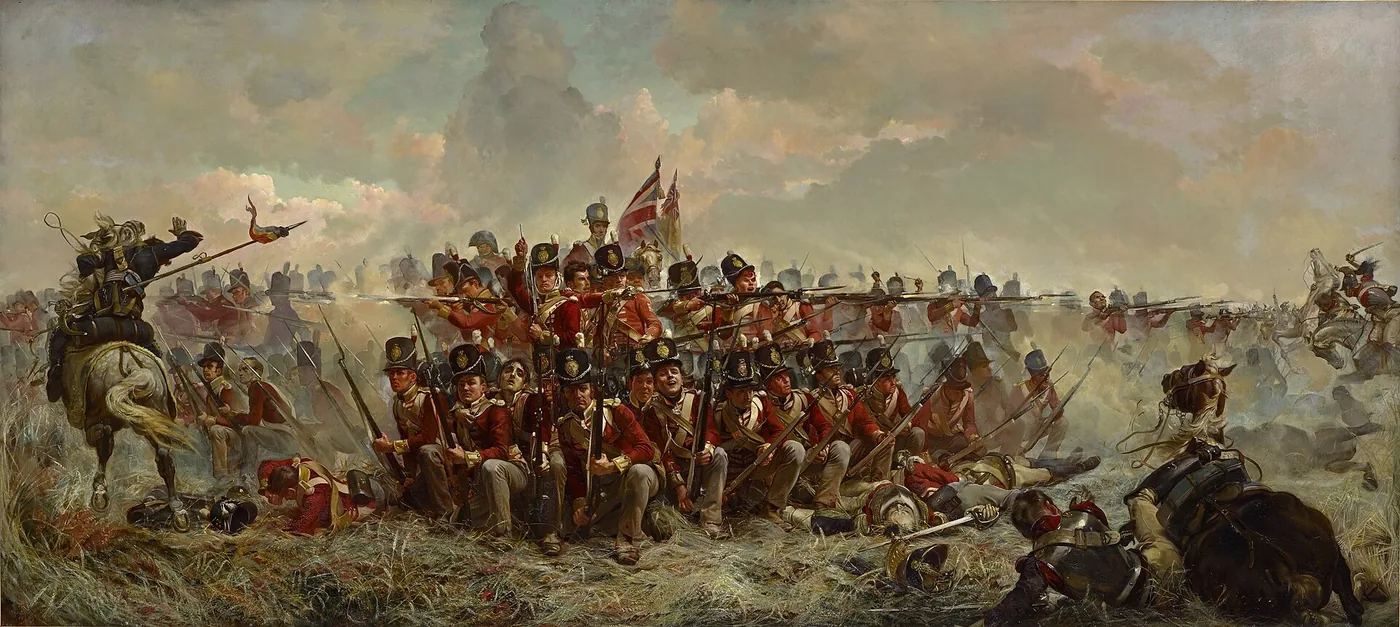 Ein Karree britischer Infanterie in roten Röcken, kniend und mit angelegten Gewehren, hält im Kornfeld einem Angriff französischer Kürassiere und Lanciers stand; im Vordergrund Verwundete und ein mit seinem Pferd gestürzter Kürassier