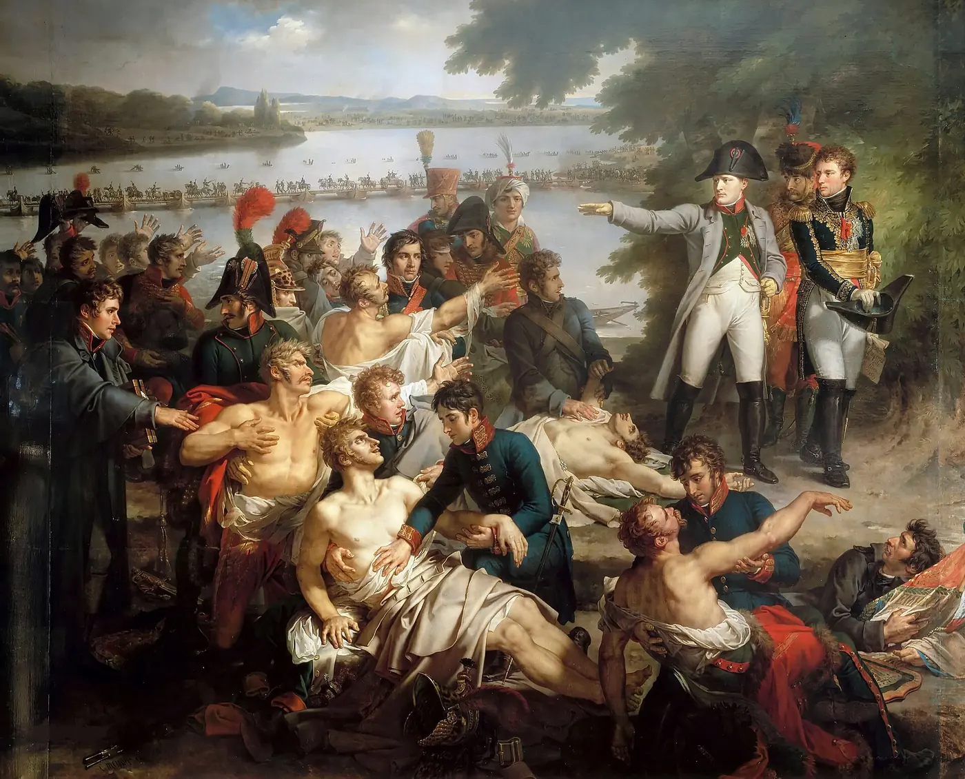 Napoléon, debout au bord du Danube avec deux officiers, tend le bras vers des blessés que l'on soigne au premier plan ; au fond, des troupes franchissent un pont de bateaux